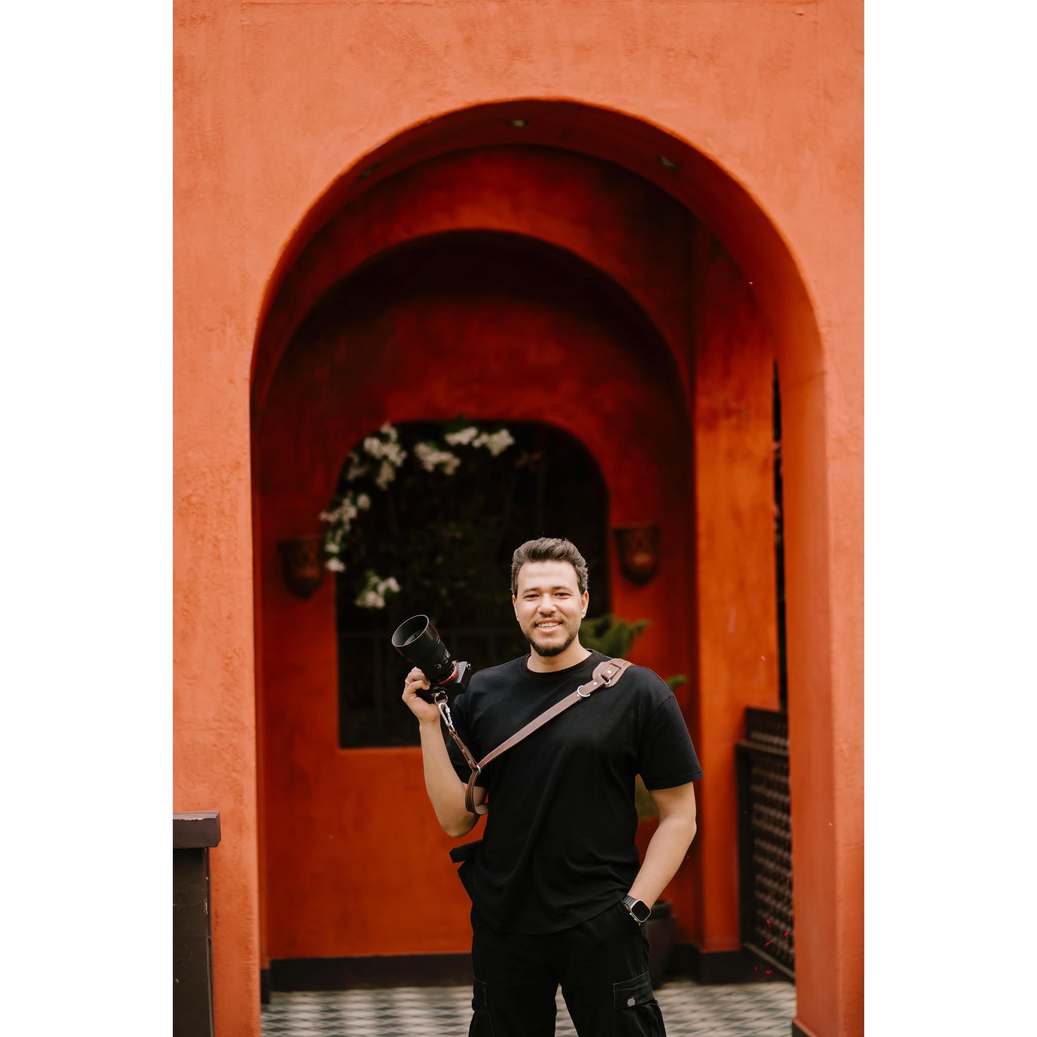 Mostafa Alarian holding his camera in a terracotta archway